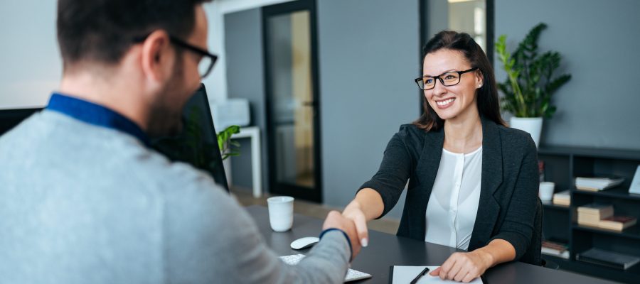 Businesswoman and businessman shaking hands in modern office.