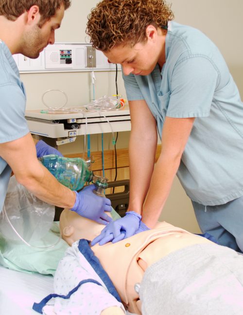 Two medical staff practicing CPR on mannequin